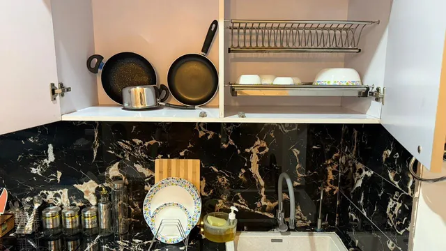 Open upper kitchen cupboards showing a dish rack and cookware storage.