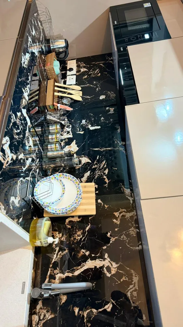 Kitchen worktop and sink details with a dark veined splashback and open storage.